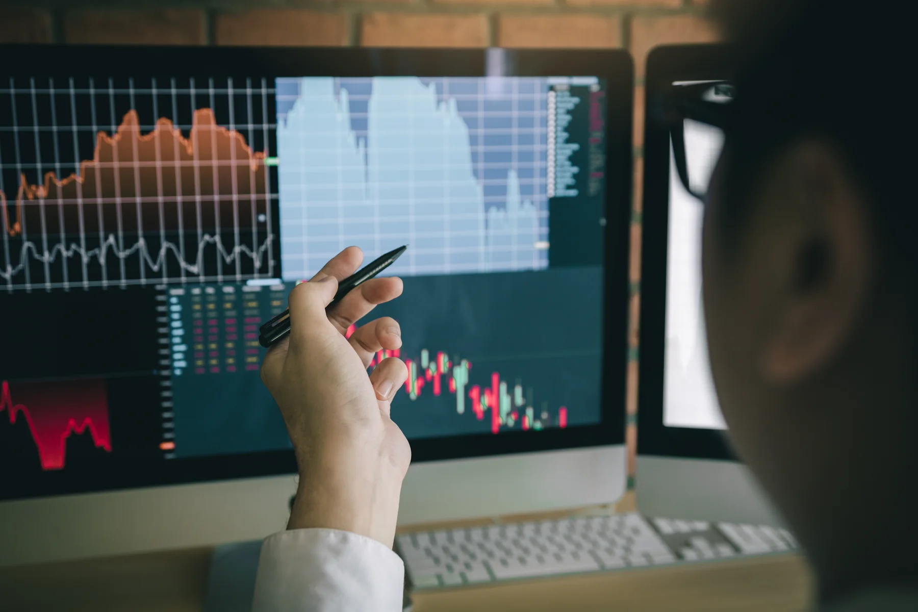 An analyst reviewing financial charts on a computer in a modern office